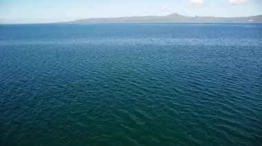 Dağların ve gökyüzünün arka planına karşı okyanus yüzeyinin drone görüntüsü. 