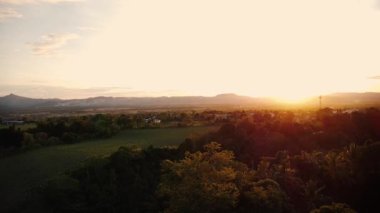 Tropikal dağların üzerinde gün batımı ve palmiye ağaçları gökyüzü manzarası. 