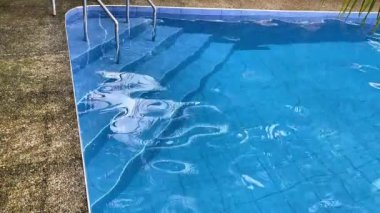 Havuza çıkan merdivenlerde suya yansıyan palmiye ağaçları var..