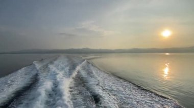 Şafak vakti bir gemiden dalgalar geliyor, gemi suyun yüzeyine doğru koşuyor, güneş denizin üzerinde.. 