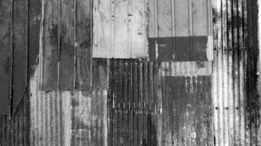 Farklı renklerde paslı malzemelerle kaplı siyah ve beyaz bir çatı. yıkım ve yıpranmış.