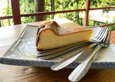 Tabakta bir parça cheesecake ve ahşap bir masa üstünde çatallar.. 
