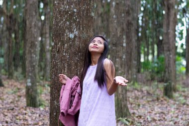güzel genç Asyalı kadın tropikal yağmurdan saklanıyor bir ağacın altında. 