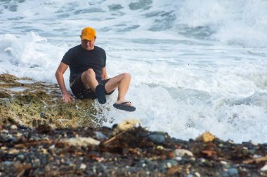 Fırtına ve yüksek dalgalar sırasında bir adam deniz kıyısında kaygan kayalara düştü. Bir adam bir dalga tarafından sürüklendi..
