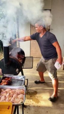 Izgarada et pişiren ve ateşte kavrulan bir adam. Izgara et yanmasın, barbekü pişirilmesin diye..