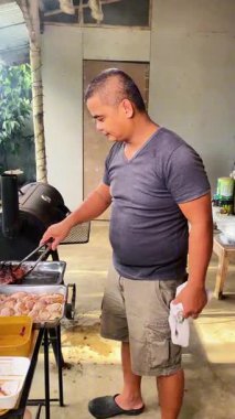 Güneydoğu Asyalı adam Filipinler 'de ateşte et pişiriyor. Kömürün üstünde ızgara et.. 