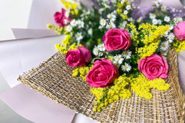 Küçük sarı çiçeklerle tamamlanmış mor kağıtta güller olan narin bir buket.. 