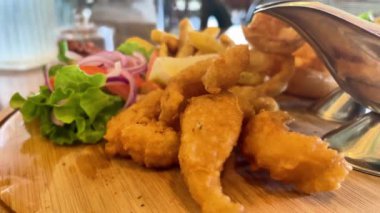 Soslu balık ve patates kızartması ve kafedeki masada patates kızartması ile sulu bir hamburger.