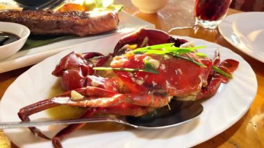 Güneş ışığı altındaki bir restoranda soslu ve baharatlı büyük bir tabak üzerinde pişmiş yengeç..