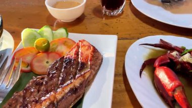 Izgara ton balığı bifteği ve bir restoranda bir tabakta pişmiş yengeç.. 