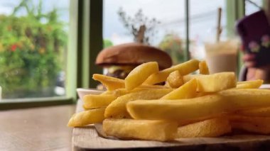 Kafedeki ahşap tepside soslu büyük sulu hamburger ve patates kızartması.. 