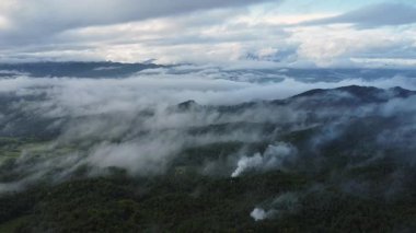Tropikal dağ manzarası ve şafak vakti bulutlar ve sisle kaplı vadi. 