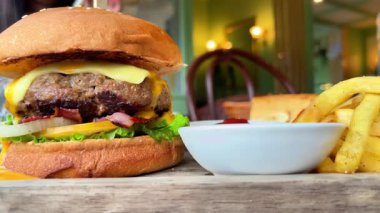 Kafedeki ahşap tepside soslu büyük sulu hamburger ve patates kızartması.. 