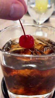 Kokteyl kirazını kola ve buzlu viski bardağına daldırıyorum..