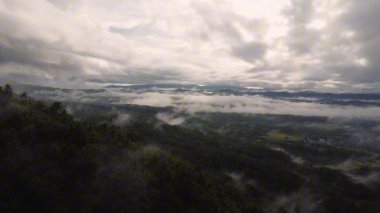 Tropikal dağ manzarası ve şafak vakti bulutlar ve sisle kaplı vadi. 