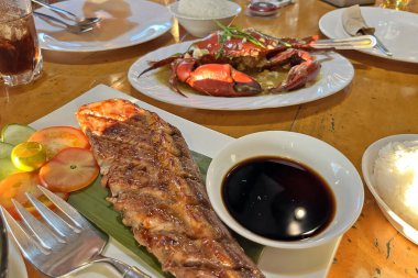 Izgara ton balığı bifteği ve bir restoranda bir tabakta pişmiş yengeç.. 