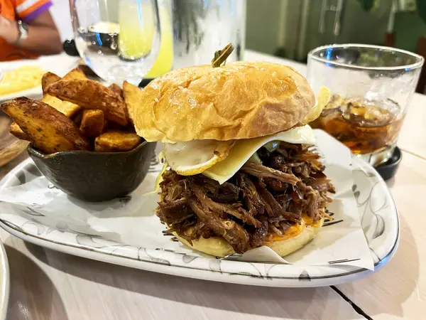 Büyük bir hamburger, fırında patates ve masada bir bardak viski..