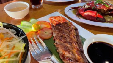 Izgara ton balığı bifteği ve bir restoranda bir tabakta pişmiş yengeç.. 