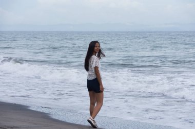 Kumlu sahilde kendine güvenen bir kadın.