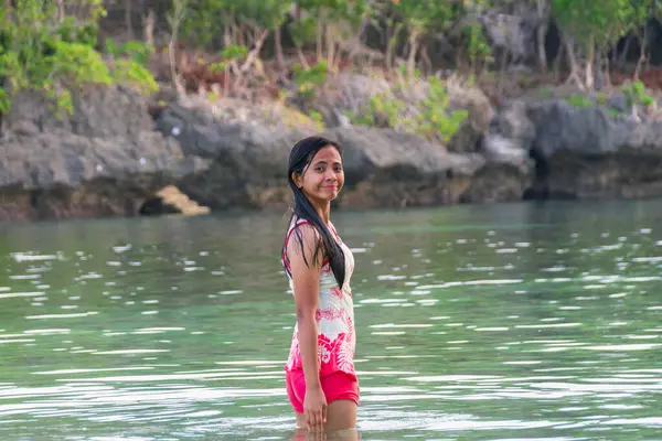 Mayo giymiş genç Asyalı kadın tropikal nehirde arkasında kayalarla dikiliyor.. 