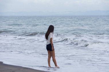 Kumlu sahilde kendine güvenen bir kadın.