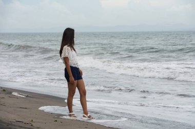 Sahilde dalgaların yanında duran kendine güvenen bir kadın..
