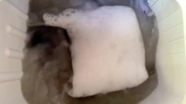 Yıkama tozu köpüğüyle kirli su çamaşır makinesinin içindeki şeylerle döner.. 