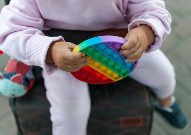 Bebek arabasındaki bir çocuk stres önleyici oyuncakla oynuyor. Patlat şunu. Seçici odak.