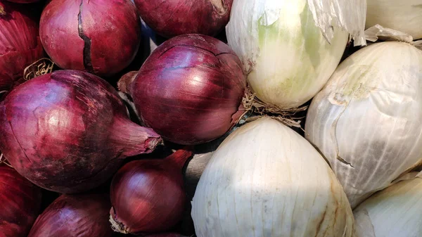 Red and white onions on a market counter.