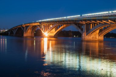 Gece metro köprüsü Kyiv 'deki Dinyeper nehri boyunca ışıkları var.