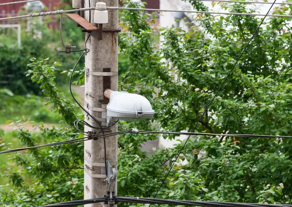 Elektrik teçhizatı ve elektrik kabloları olan bir direk. Lamba direği.