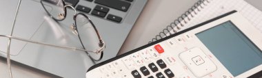 Gri arkaplanda hesap makinesi laptopu ve gözlük
