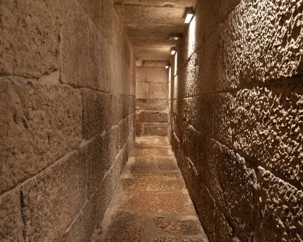 Bir şatoda dar taş koridor, aydınlatmalı piramit ya da kilise