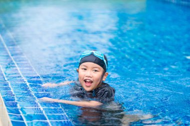Mutlu çocuklar, yüzme havuzunda güneş gözlüklü şirin bir kız.