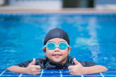 Mutlu çocuklar, yüzme havuzunda güneş gözlüklü şirin bir kız.