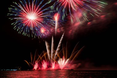 Geceleyin çeşitli renklerde renkli havai fişekler ve kutlama ve yıldönümü konsepti.