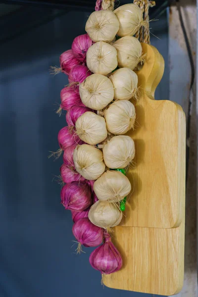 Garlic, onion and chilli, autumn season product, hanging on wooden logs in kitchen.