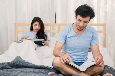 Genç seven çift yatak odalı evde üzerine bir kitap okuma.