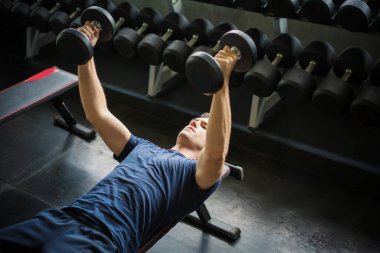 Ağırlık kaldıran yakışıklı halterci spor salonunda halterle çalışıyor.