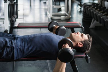 Ağırlık kaldıran yakışıklı halterci spor salonunda halterle çalışıyor..