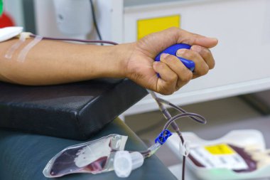 Elinde şişme bir topla kan bağışı yapan bir adam..