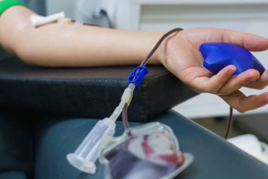 Kan bağışı yapan bir kadın elinde şişme bir topla..