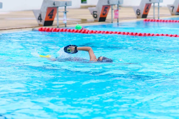 Çocuk yüzücü yüzme havuzunda yüzer. Su sporları eğitimi ve yarışma, çocuklar için yüzme dersleri..