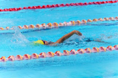 Yüzücü çocuk yüzme havuzunda sırt üstü yüzer. Su sporları ve yarışma, çocuklar için yüzme dersleri..