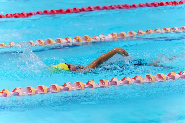Yüzücü çocuk yüzme havuzunda sırt üstü yüzer. Su sporları ve yarışma, çocuklar için yüzme dersleri..