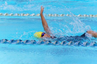 Yüzücü çocuk yüzme havuzunda sırt üstü yüzer. Su sporları ve yarışma, çocuklar için yüzme dersleri..