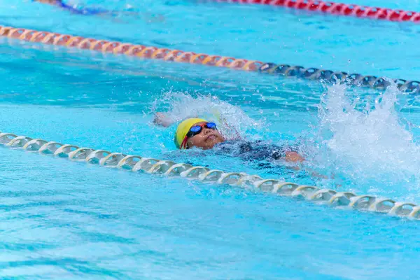 Yüzücü çocuk yüzme havuzunda sırt üstü yüzer. Su sporları ve yarışma, çocuklar için yüzme dersleri..