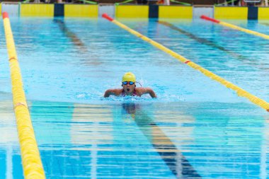 Yüzücü çocuk yüzme havuzunda kelebek yüzme stili yüzer. Su sporları ve yarışma, çocuklar için yüzme dersleri..