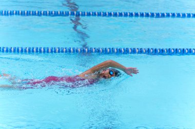 Yüzücü çocuk yüzme havuzunda serbest yüzme stili yüzer. Su sporları ve yarışma, çocuklar için yüzme dersleri..