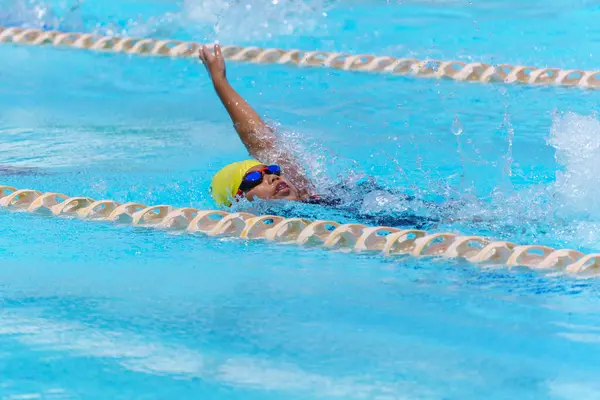 Yüzücü çocuk yüzme havuzunda sırt üstü yüzer. Su sporları ve yarışma, çocuklar için yüzme dersleri..